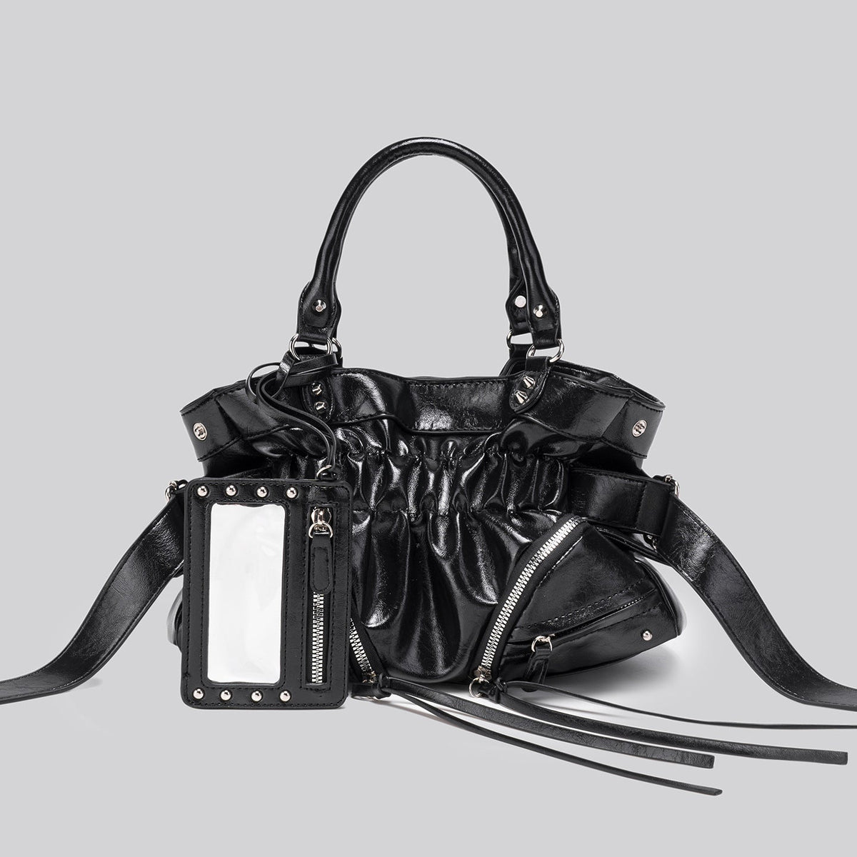 Black glossy ruched convertible tote bag with silver-tone rivets, detachable wide shoulder strap, external zip pouch, and