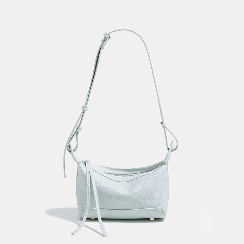 Small structured mini crossbody shoulder bag with pebbled texture, knotted adjustable strap, top zip closure, and gold-tone