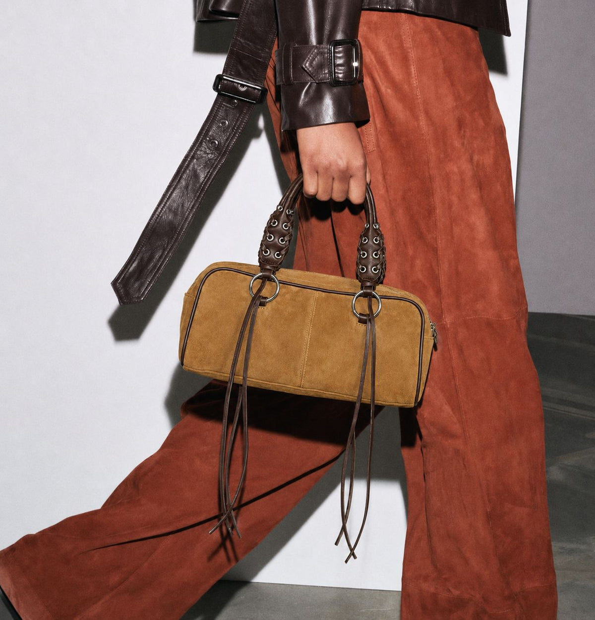 Rectangular suede-look barrel bag with laced eyelet handles, silver O-ring hardware, and hanging leather-look fringe tie