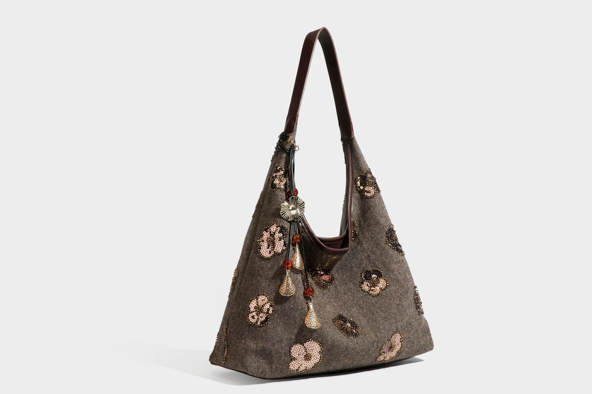 Lässig fallende, trapezförmige Schulter-Tote in Anthrazitgrau mit floralen Paillettenmotiven in Silber, Riemen in Lederoptik und herabhängendem Perlenbesatz