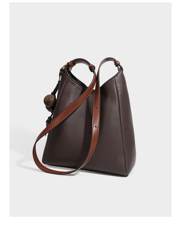 Hobo-Schultertasche in dunklem Espresso mit genarbter Oberfläche, warmen cognacfarbenen Details, verstellbarem schmalem Riemen, goldfarbenen Ringbeschlägen und geknotetem