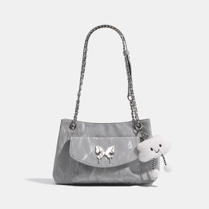 Soft rectangular glossy leather-look shoulder bag with silver chain strap, butterfly ornament on front flap pocket, and