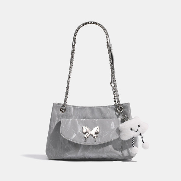 Soft rectangular glossy leather-look shoulder bag with silver chain strap, butterfly ornament on front flap pocket, and
