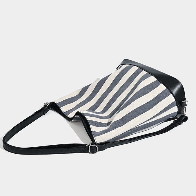 Wandelbarer Tote-Rucksack aus Canvas mit blau-weißen vertikalen Streifen, lederähnlichen Besätzen und silberfarbenen Metalldetails, Detailansicht