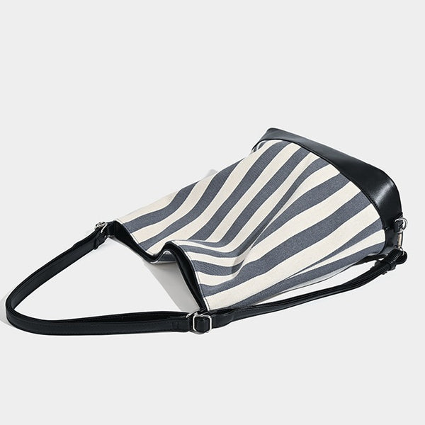 Wandelbarer Tote-Rucksack aus Canvas mit blau-weißen vertikalen Streifen, lederähnlichen Besätzen und silberfarbenen Metalldetails, Detailansicht