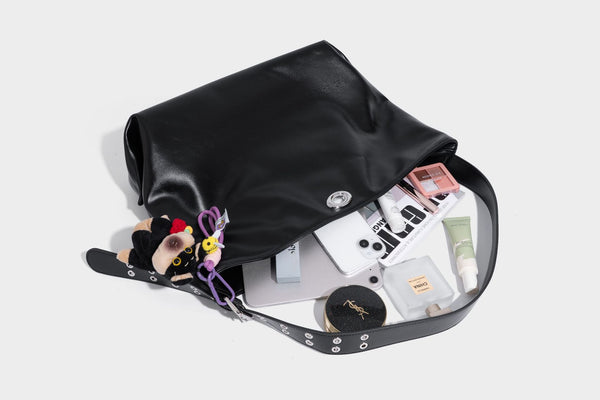 Große schwarze, glänzende Hobo-Schultertasche in Lederoptik mit mit Ösen besetztem Riemen, silberfarbenen Beschlägen und abnehmbarem
