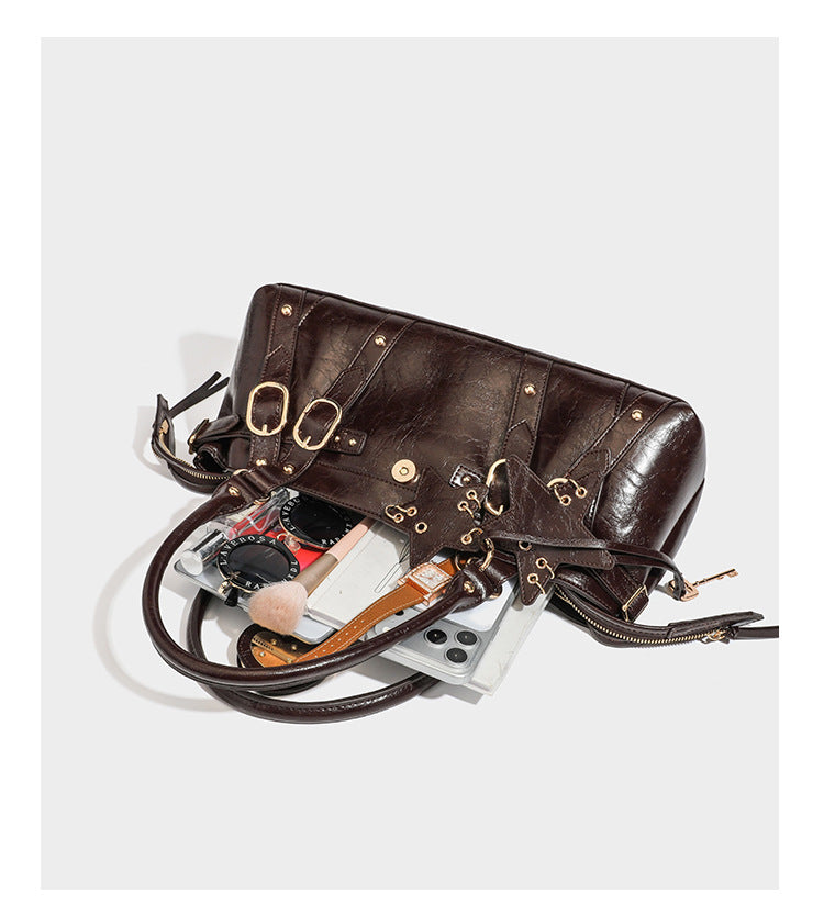 Dark brown glossy crinkled leather-look barrel bag with gold heart lock, dome studs, star charm, dual top handles and, detail