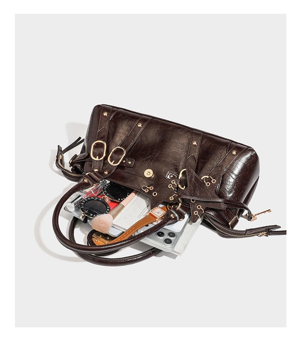 Dark brown glossy crinkled leather-look barrel bag with gold heart lock, dome studs, star charm, dual top handles and, detail