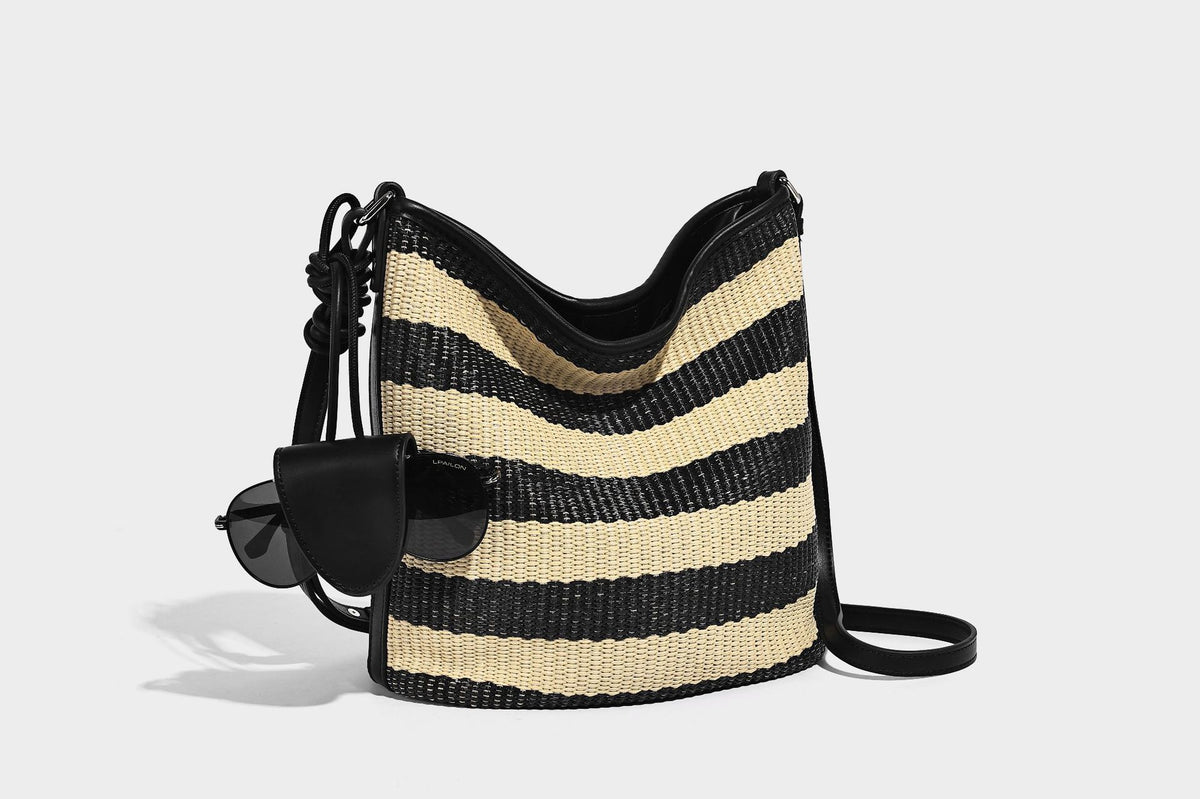 Gestreifte gewebte Bucket Bag in Schwarz und Beige mit schwarzem Besatz in Lederoptik, offener Oberseite und langem verstellbarem Schulterriemen, Detailansicht