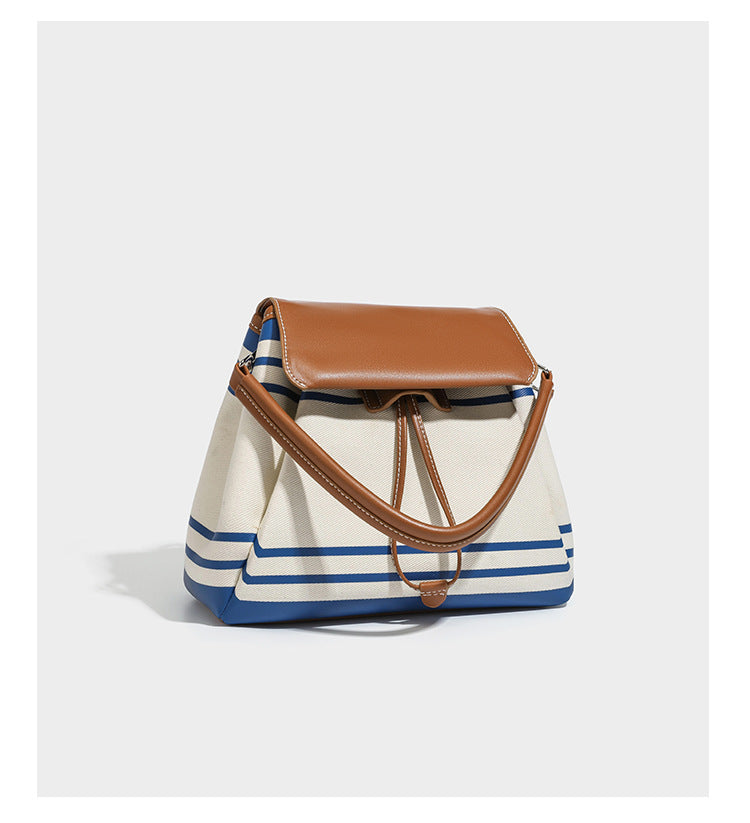 Cream canvas bucket bag with blue horizontal stripes, tan leather-look flap and trim, drawstring closure, silver-tone, detail