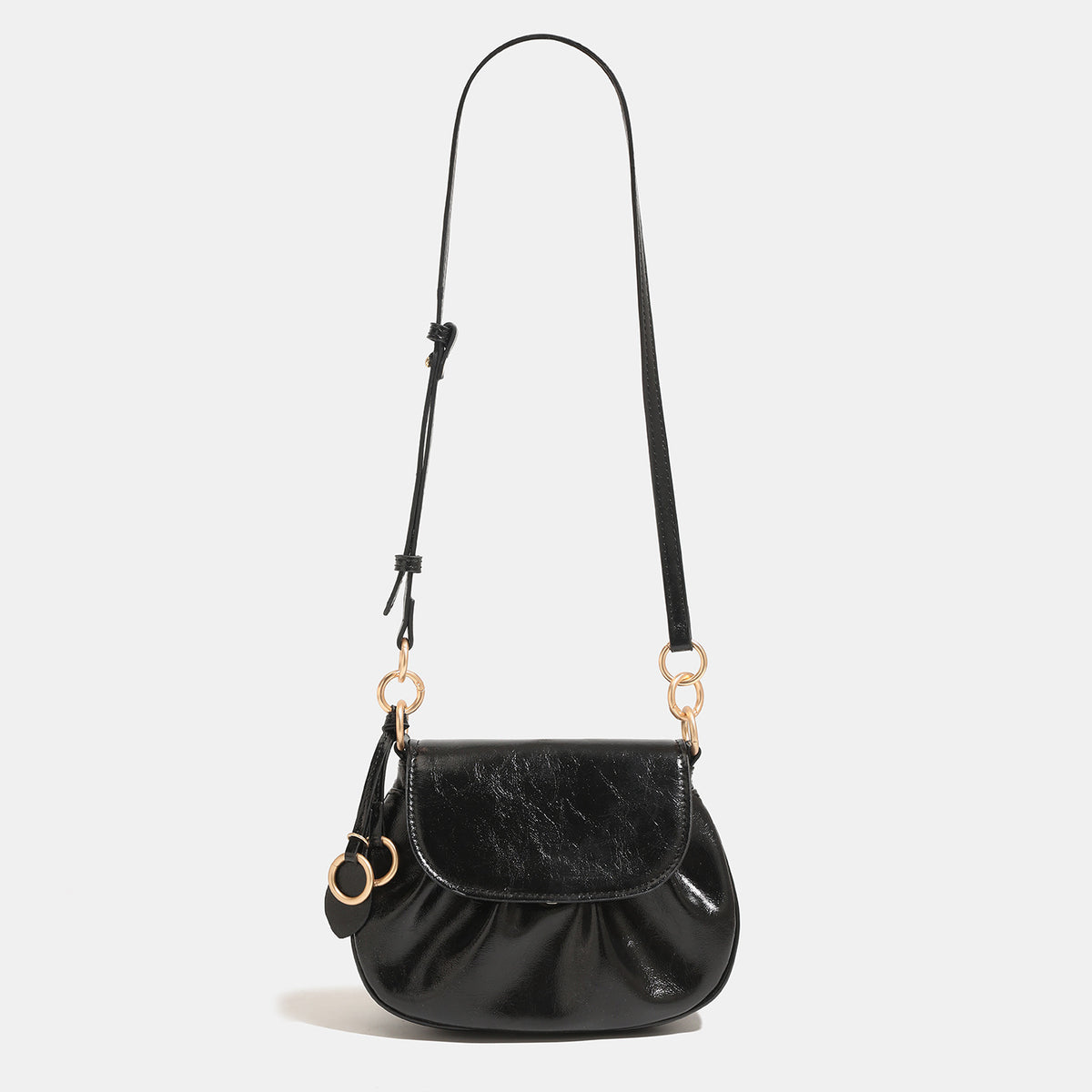 Small rounded flap crossbody saddle bag with gold-tone ring hardware and adjustable strap, detail view 6
