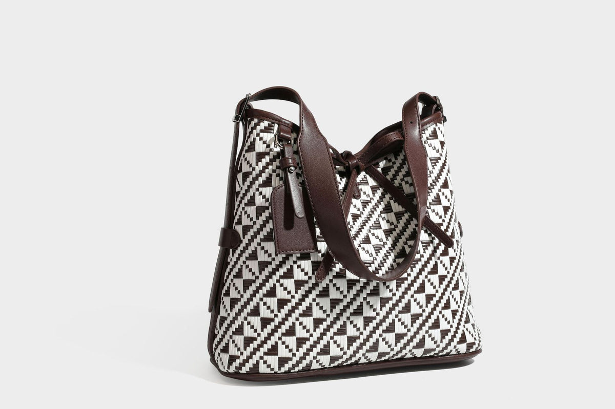 Woven geometric bucket shoulder bag in white and dark brown two-tone pattern with leather-look trim and drawstring top