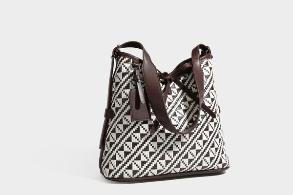 Woven geometric bucket shoulder bag in white and dark brown two-tone pattern with leather-look trim and drawstring top