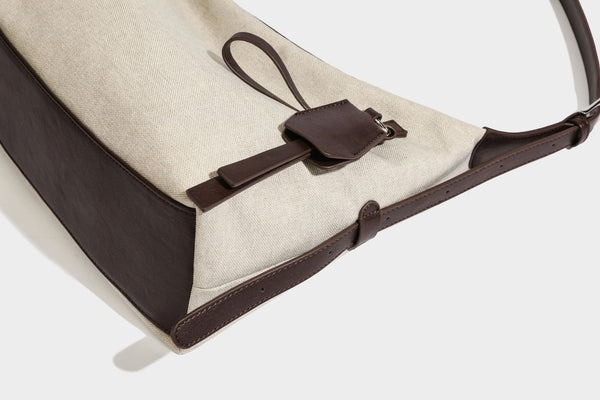 Lässige Hobo-Schultertasche aus haferfarbenem Canvas mit dunkelbraunen Besätzen in Lederoptik, silberfarbenem Reißverschluss und langem, verstellbarem