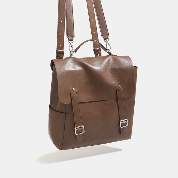 Structured flap backpack handbag in smooth leather-look finish with buckle front pocket, top handle, and silver-tone