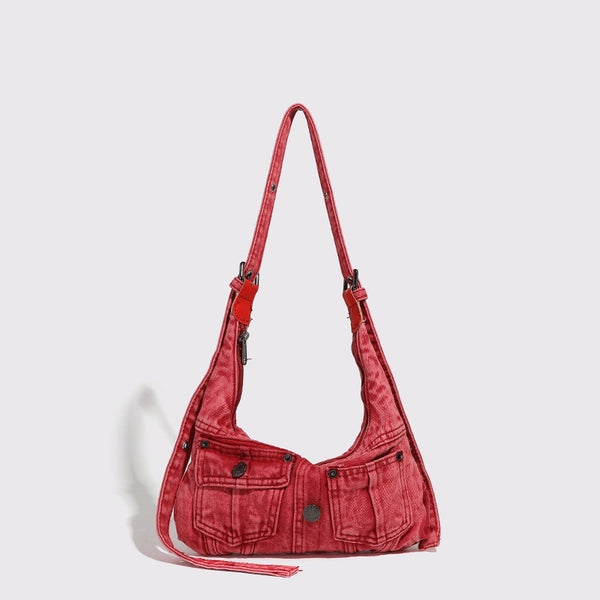 Compact washed red distressed-textile shoulder bag with front flap pockets, dark metal hardware, and long adjustable strap