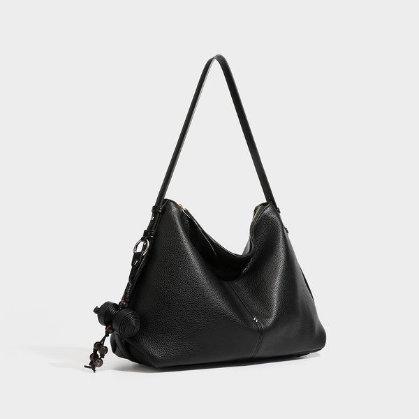 Slouchy hobo shoulder bag with pebbled leather-look finish, zip-top closure, gold-tone hardware, and hanging bead charm