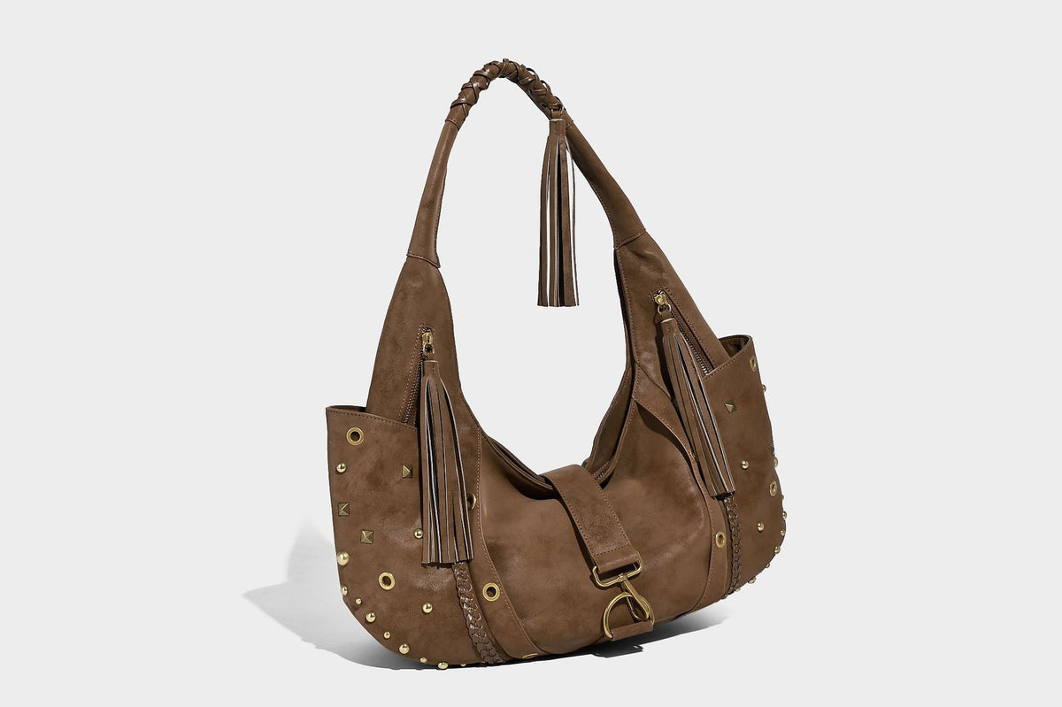 Slouchy crescent hobo bag in matte brown suede-like finish with gold-tone studs, grommets, braided top handle, tassel side