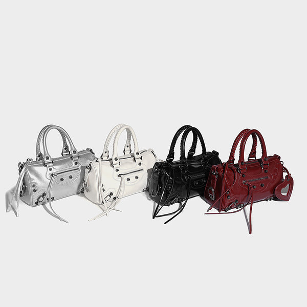 Glossy studded mini satchel bag with braided top handles, front zip pocket, heart charm, and detachable crossbody strap