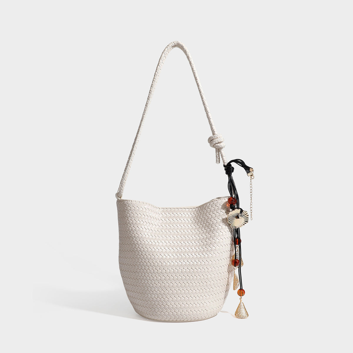 Olive green woven leather-look bucket bag with braided crossbody strap, knotted adjustment, and gold-tone tassel charm with