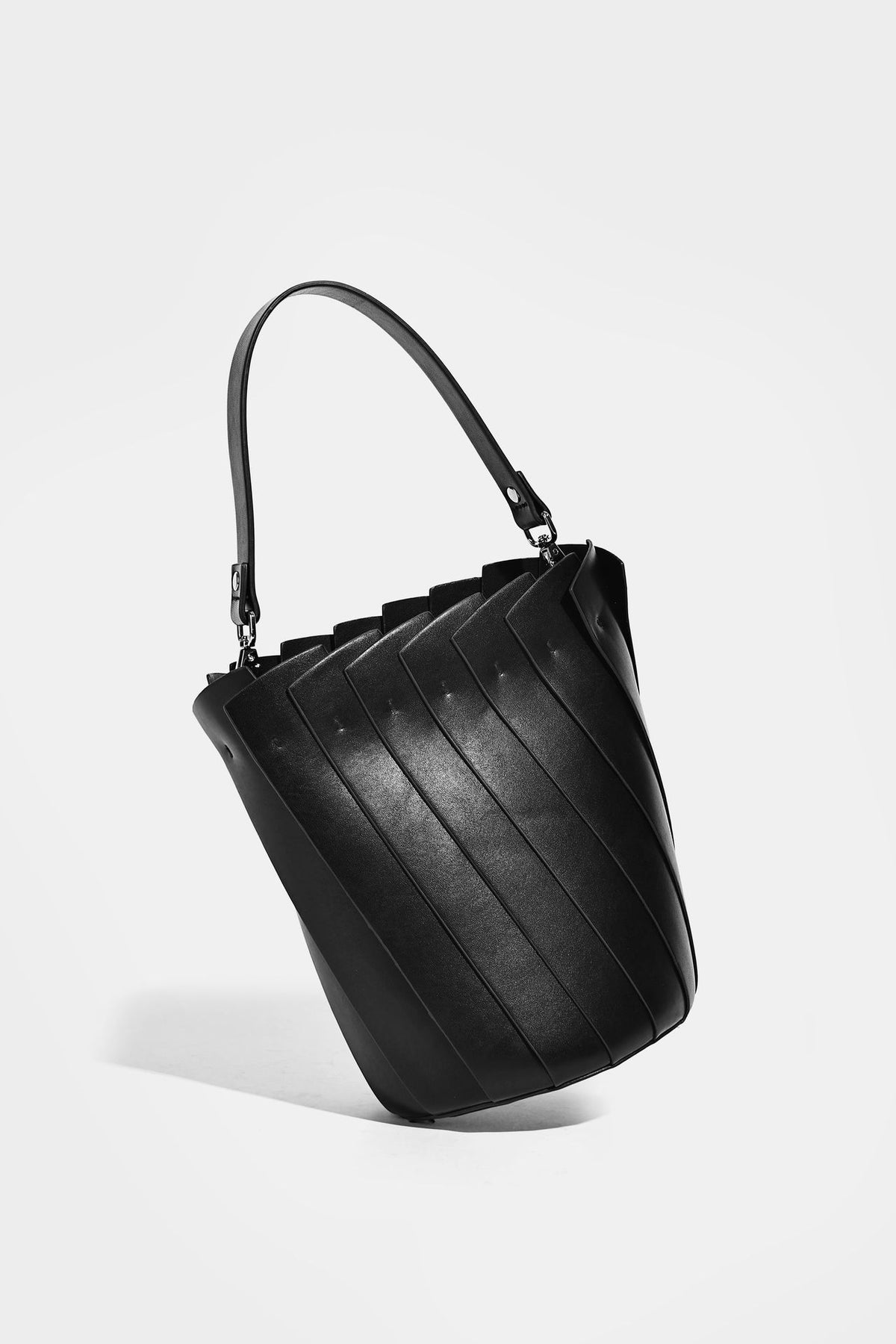 Structured pleated-panel bucket bag with curved top handle and detachable adjustable shoulder strap in smooth matte, detail