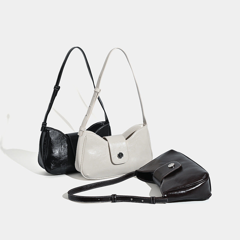 Compact glossy leather-look shoulder bag with round metal snap closure and contrast stitching, detail view 2