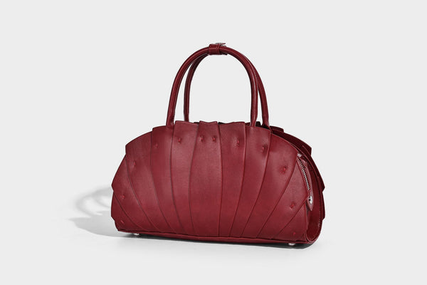 Structured dome satchel with fan-pleated leather-look exterior, dual top handles, and detachable shoulder strap, detail view