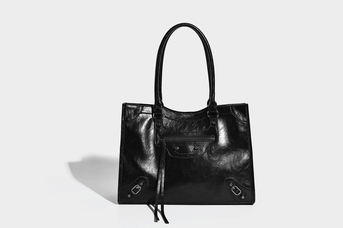 Large structured leather-look tote bag with front zip pocket, moto hardware accents, and long double shoulder straps, detail