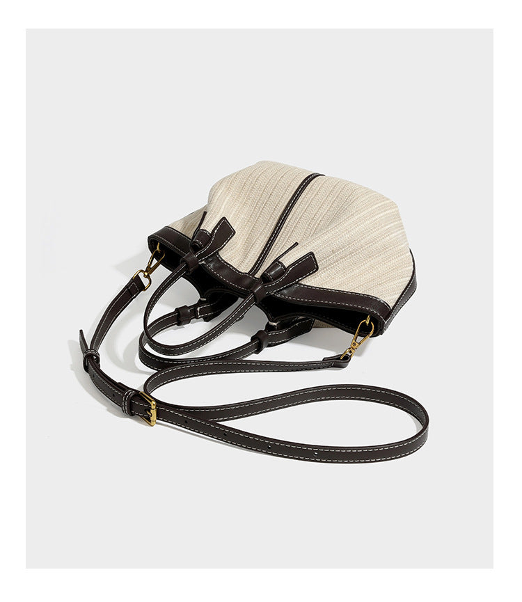 Cremefarbene geflochtene Tote-Bag mit dunkelbraunen Besätzen in Lederoptik, kontrastierenden weißen Nähten, zwei oberen Henkeln und abnehmbarem Schulter