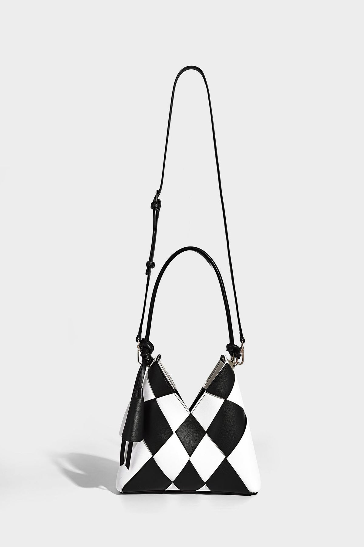 Compact bucket shoulder bag with black-and-white diamond patchwork panels, knotted top handle, gold-tone hardware, and