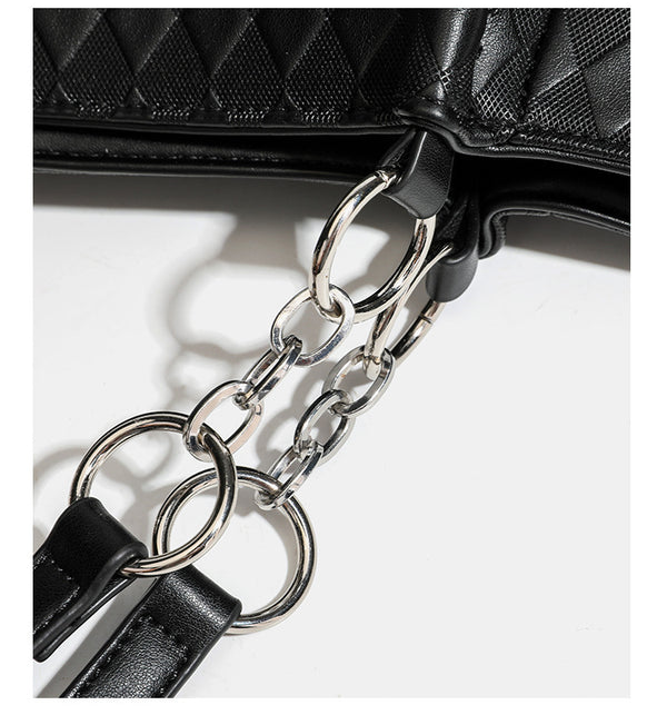 Black diamond-quilted leather-look tote bag with silver chain-ring shoulder straps and plush bear charm pendant, detail view