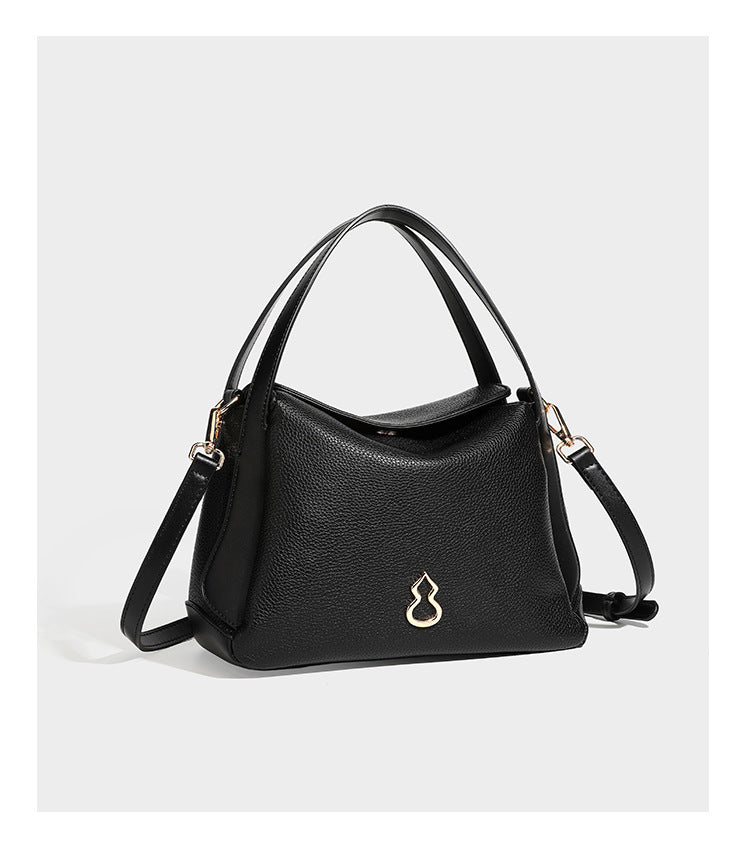 Structured pebbled leather-look shoulder bag with flap top, gold-tone emblem hardware, dual top handles, and detachable