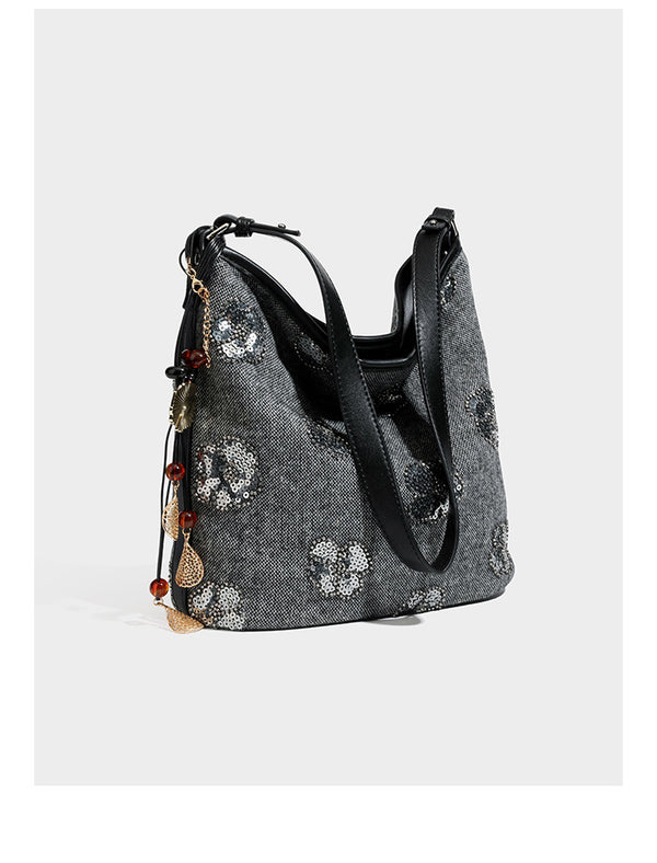 Lässig fallende Hobo-Schultertasche aus anthrazitfarbenem Webstoff mit floraler Stickerei aus silberfarbenen Pailletten, schwarzem Besatz in Lederoptik und langem