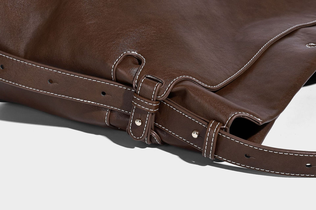 Large slouchy leather-look hobo tote bag with open top, adjustable shoulder strap, and colorful tassel bead charm, detail