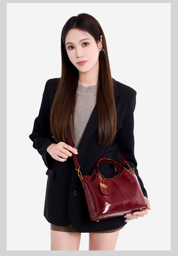 Structured crinkle-gloss top-handle satchel in deep burgundy with antique gold lock charm and detachable shoulder strap
