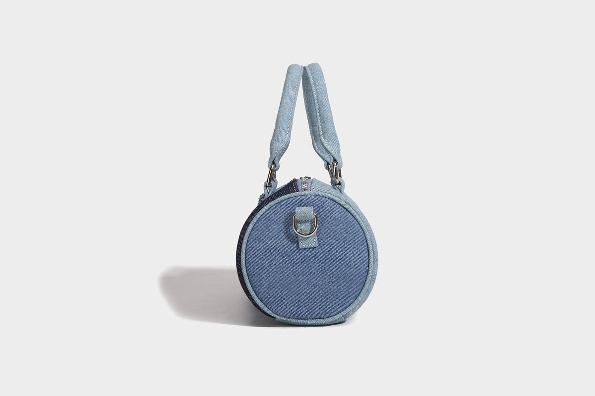 Mini barrel handbag in light and dark denim patchwork with frayed seam trim, dual top handles, top zip closure, and, detail