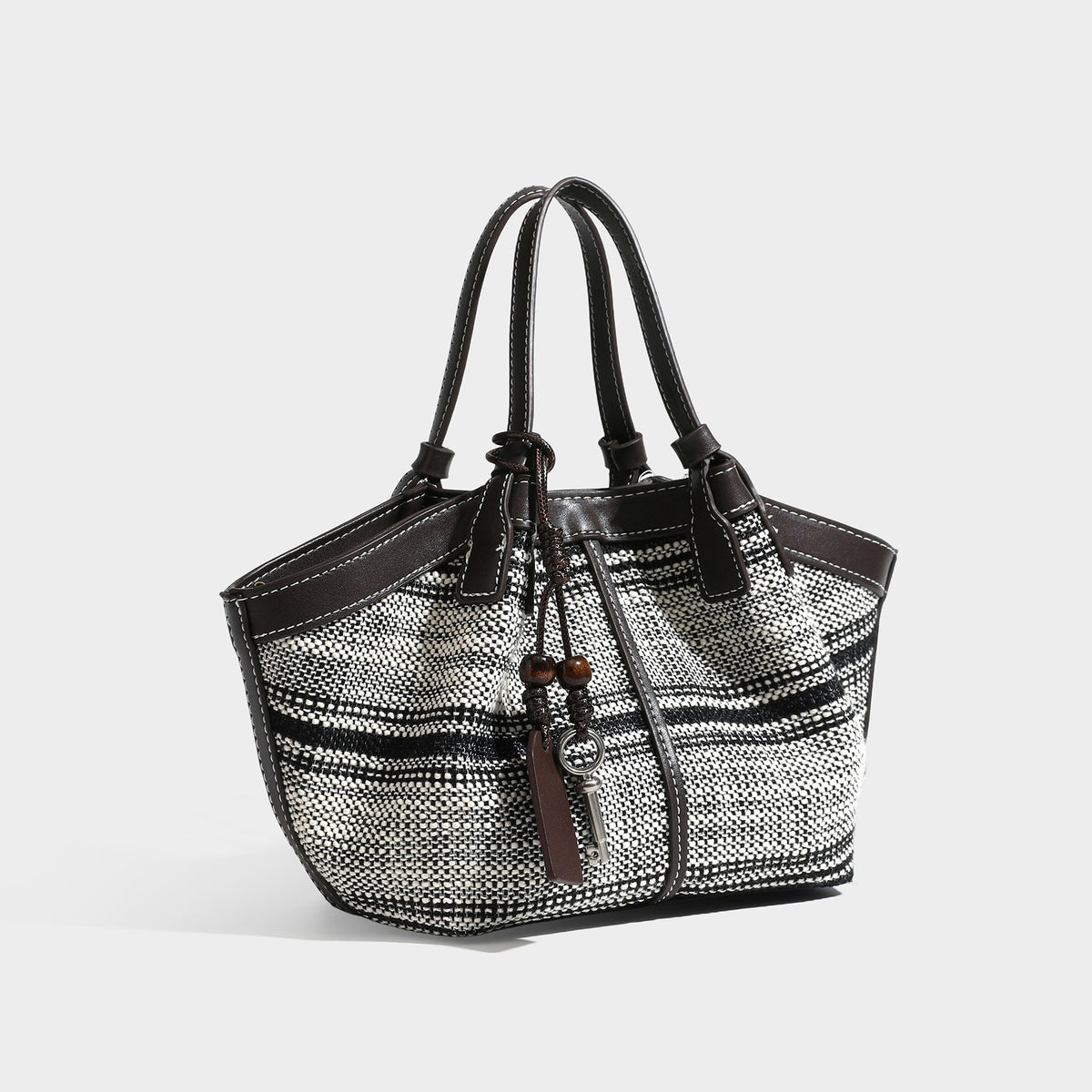 Schwarz-weiße gewebte Trapez-Tote-Bag mit dunklem Lederimitat-Besatz, weißen Kontrastnähten und zwei Henkeln, Detailansicht