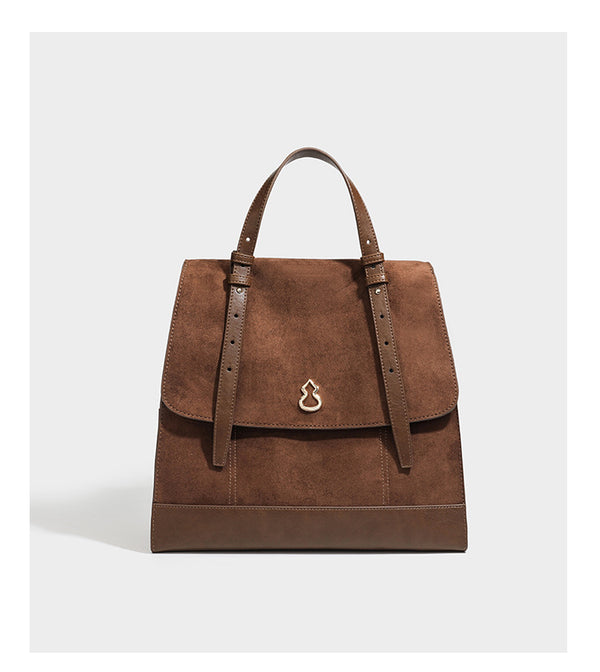 Structured suede-look convertible backpack handbag with flap closure and gold-tone emblem hardware in chocolate brown, detail