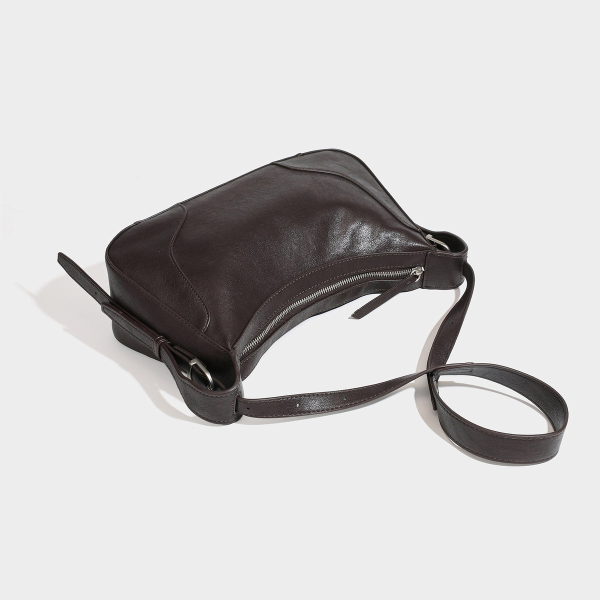 Dark brown curved zip-top hobo shoulder bag with slim adjustable strap and silver-tone hardware, detail view 4