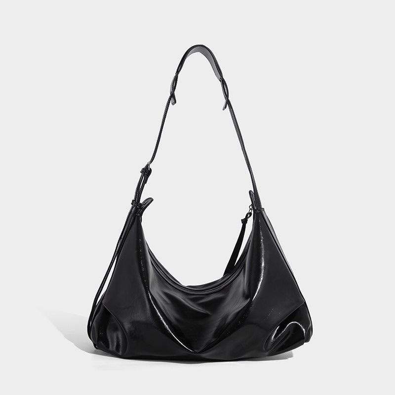 Glossy black slouchy hobo shoulder bag with zip closure, silver-tone ring hardware, and adjustable crossbody strap, detail