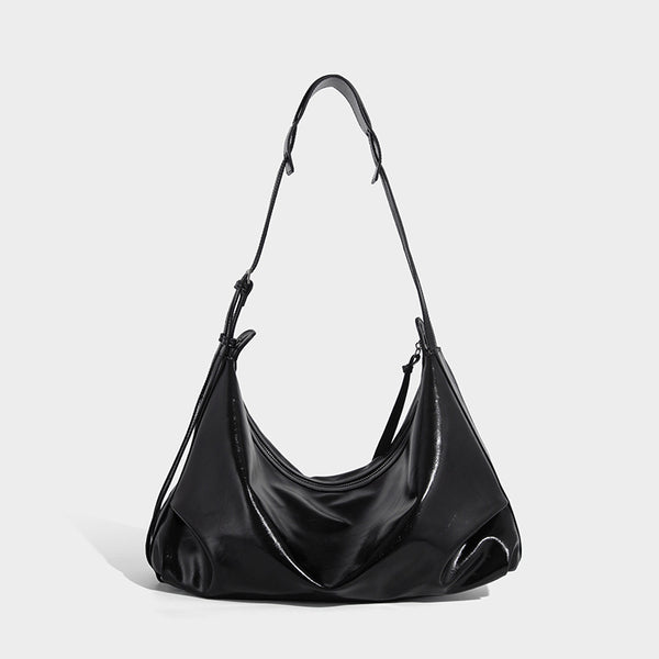 Glossy black slouchy hobo shoulder bag with zip closure, silver-tone ring hardware, and adjustable crossbody strap, detail