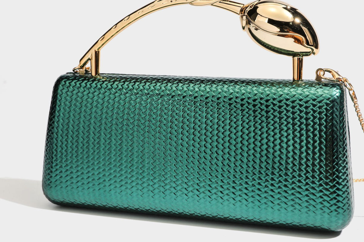 Structured rectangular metallic woven clutch bag with sculptural gold-tone leaf top handle and detachable chain strap, detail