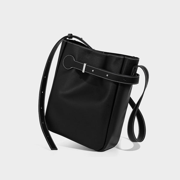 Structured dark brown leather-look bucket bag with white contrast stitching, front wraparound belt buckle strap, and long