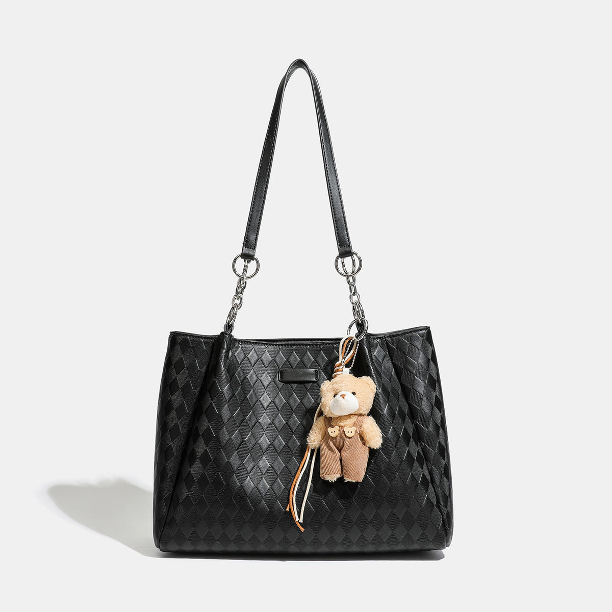 Black diamond-quilted leather-look tote bag with silver chain-ring shoulder straps and plush bear charm pendant, detail view