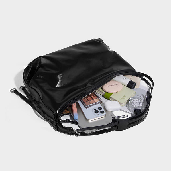 Glossy black slouchy hobo shoulder bag with zip closure, silver-tone ring hardware, and adjustable crossbody strap, detail