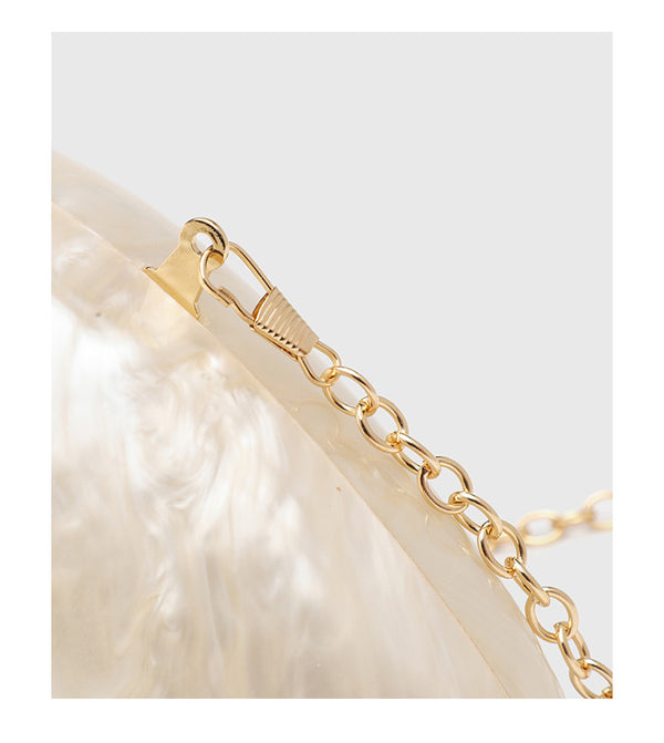 Ovale Hartschalen-Clutch in marmorierter Perlmuttoptik mit Verschluss aus zwei goldfarbenen Kugeln und goldfarbener Kettenriemen, Detailansicht