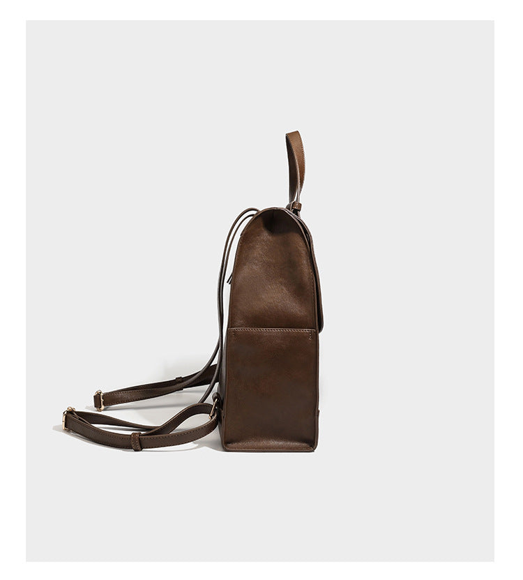 Structured suede-look convertible backpack handbag with flap closure and gold-tone emblem hardware in chocolate brown, detail