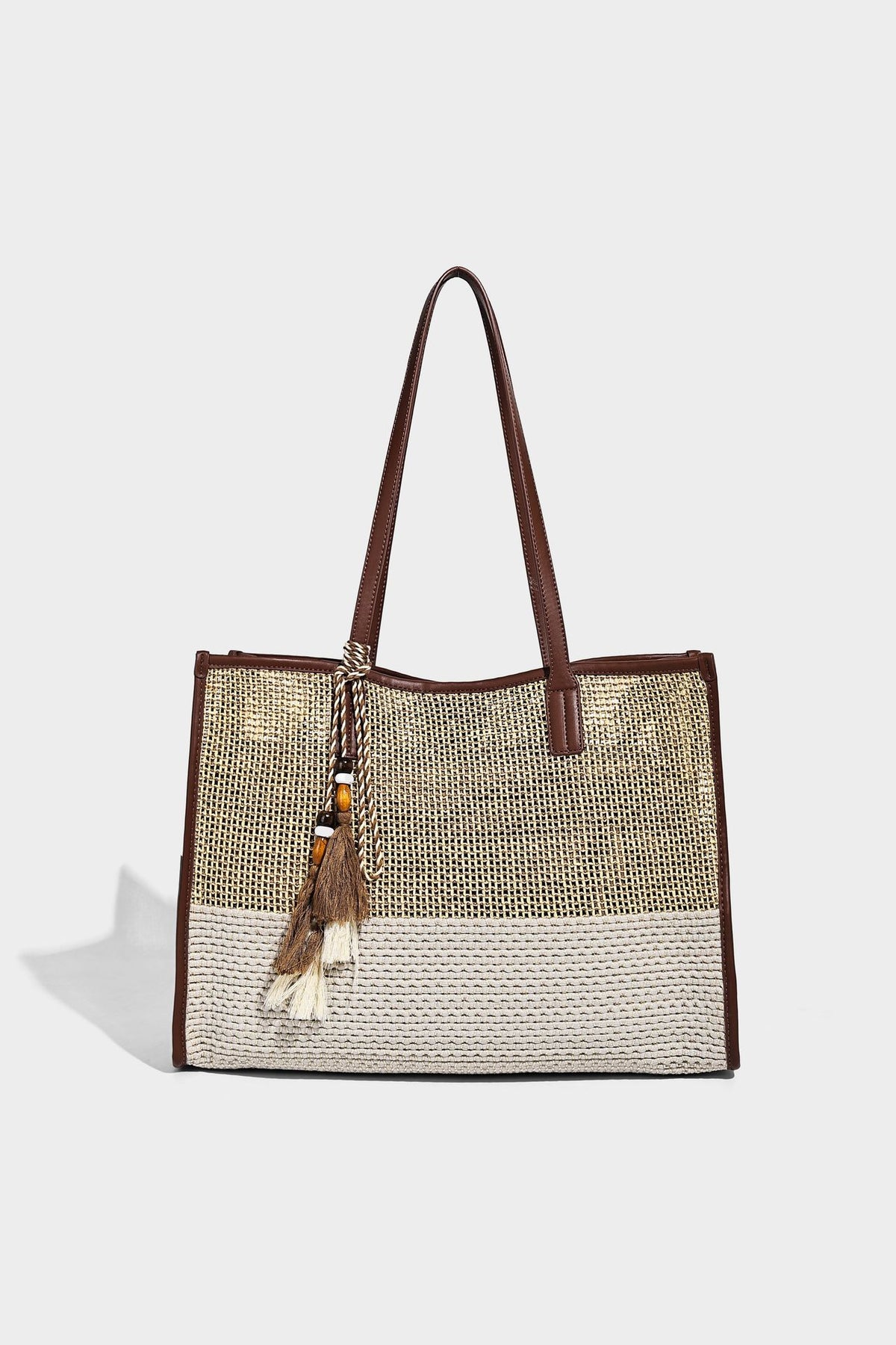 Große Tote-Bag aus grob geflochtenem Stroh in Beige und Creme mit dunkelbraunen Details in Lederoptik, langen Schulterriemen und einem mit Perlen verzierten