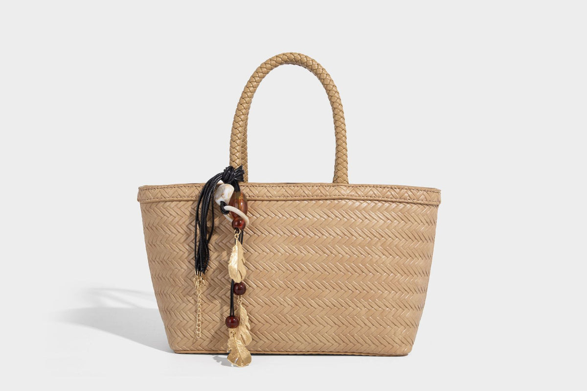 Structured chevron woven leather-look tote bag with braided top handles, gold feather charm, and adjustable shoulder strap