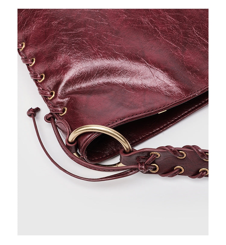 Large slouchy hobo shoulder bag with braided top handle, gold-tone O-ring hardware, and lace-up side cord detailing in